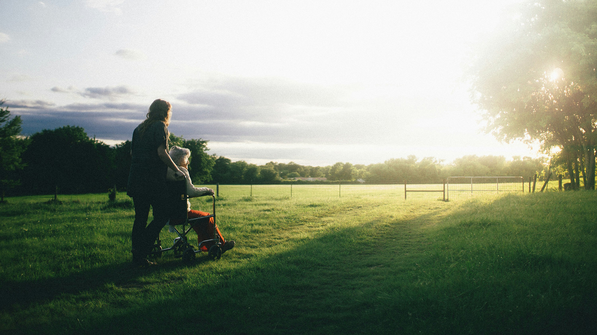 Care worker with wheel-chaired patient in an idyllic rural setting