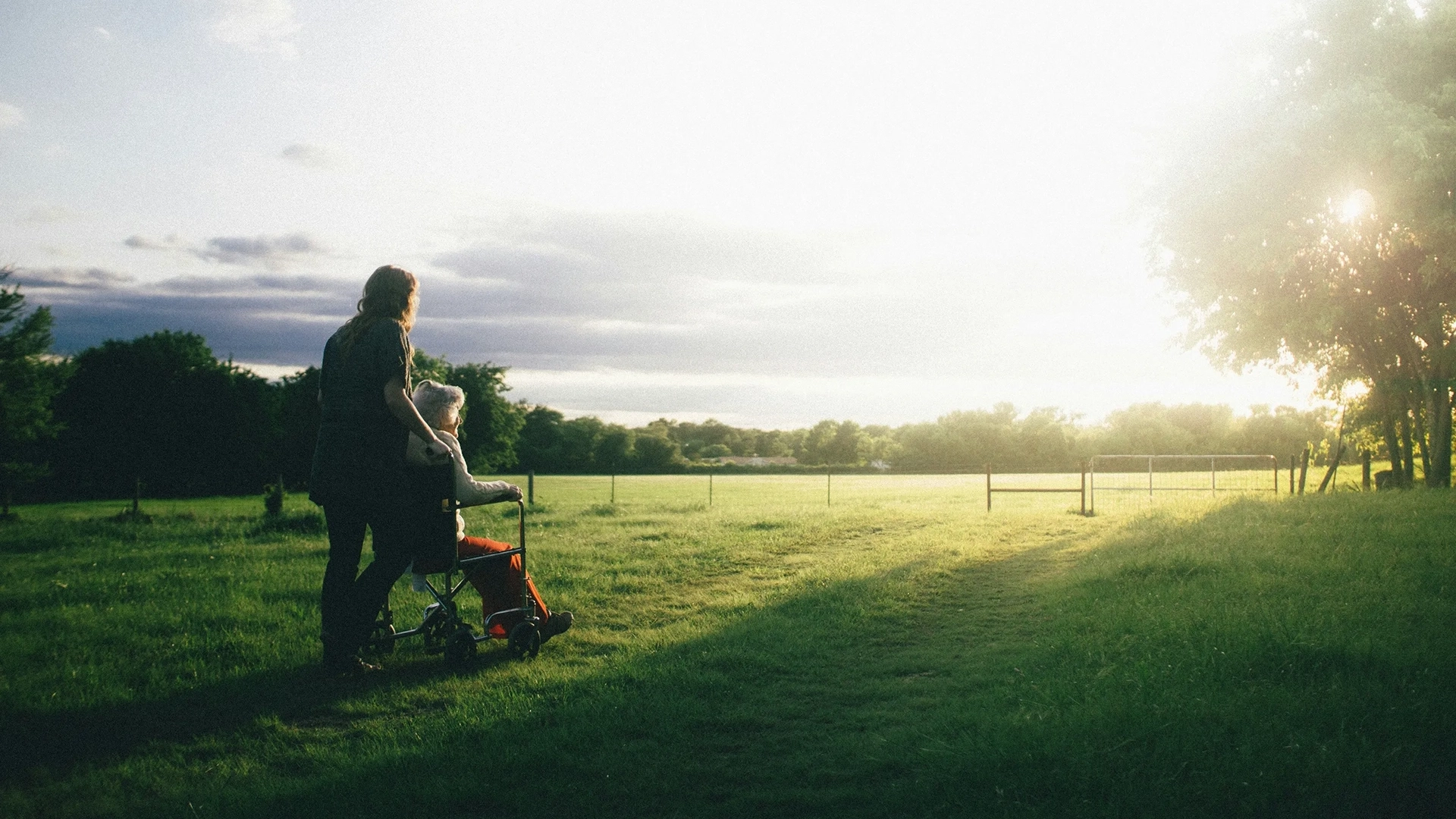 Care worker with wheel-chaired patient in an idyllic rural setting